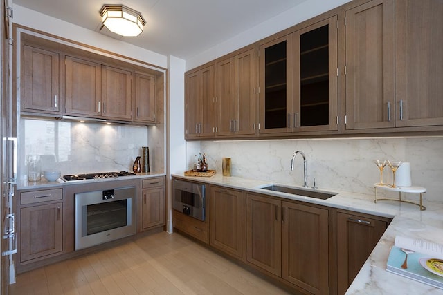 30 Park Pl Unit 64B, New York City, NY 10007 - kitchen with stainless steel appliances, backsplash, brown cabinets, light wood finished floors, and glass insert cabinets