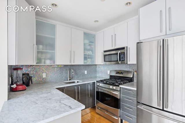 3001 Fort Hamilton Pkwy Unit 3B, New York City, NY 11218 - kitchen featuring appliances with stainless steel finishes, a sink, light stone countertops, white cabinets, and decorative backsplash