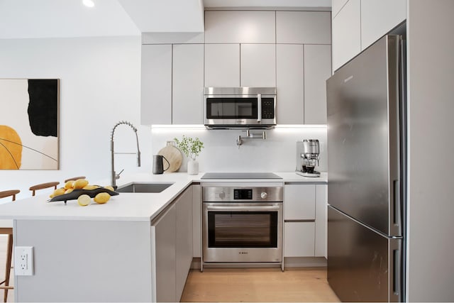 106 Jefferson Ave Unit 4, New York City, NY 11216 - kitchen with appliances with stainless steel finishes, a peninsula, a sink, modern cabinets, and light countertops