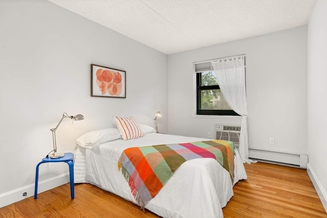 1885 Lexington Ave Unit 5D, New York City, NY 10035 - bedroom with a baseboard heating unit, wood finished floors, baseboards, and a wall mounted AC