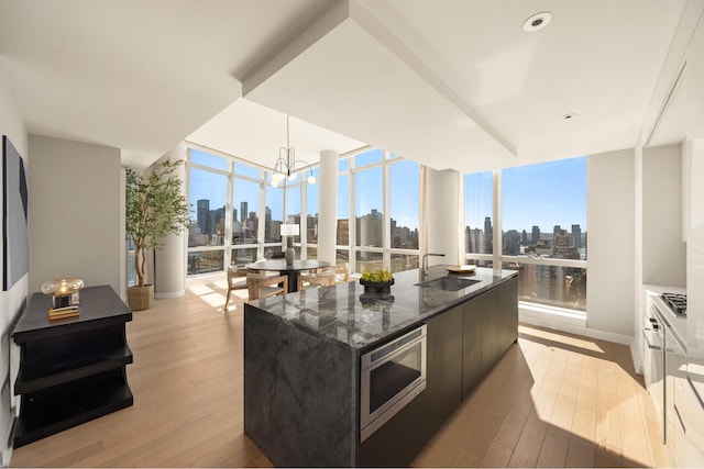 400 Park Ave S Unit 26C, New York City, NY 10016 - kitchen featuring a view of skyline, stainless steel appliances, expansive windows, a sink, and light wood-style flooring