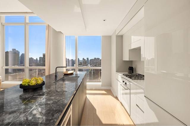 400 Park Ave S Unit 26C, New York City, NY 10016 - kitchen featuring a sink, modern cabinets, a view of skyline, white cabinetry, and expansive windows