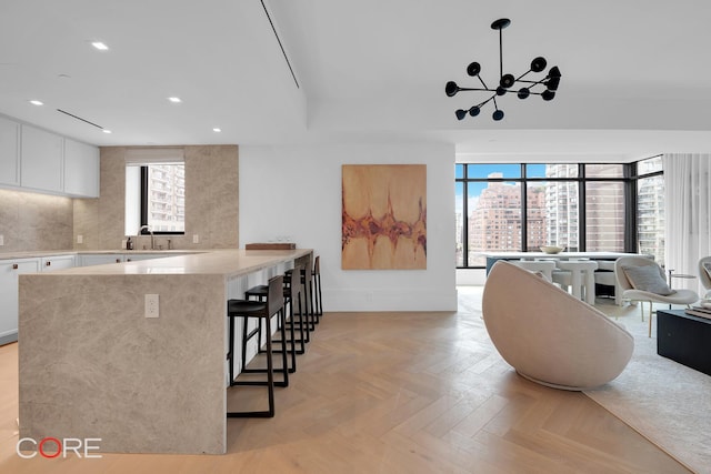 310 E 86th St Unit 14B, New York City, NY 10028 - kitchen with white cabinets, a kitchen bar, recessed lighting, a chandelier, and a peninsula