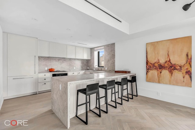 310 E 86th St Unit 14B, New York City, NY 10028 - kitchen with a kitchen breakfast bar, white cabinetry, a peninsula, and light countertops