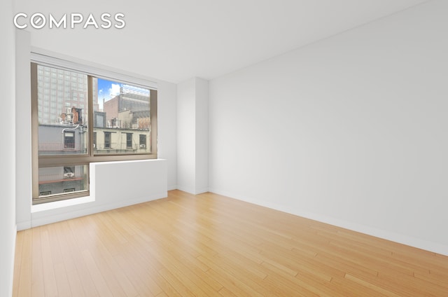 242 E 25th St Unit 5B, New York City, NY 10010 - spare room featuring wood finished floors and baseboards