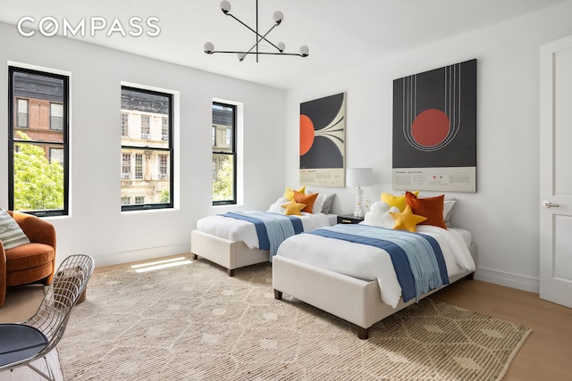 53 W 85th St, New York City, NY 10024 - bedroom featuring multiple windows, a chandelier, baseboards, and wood finished floors