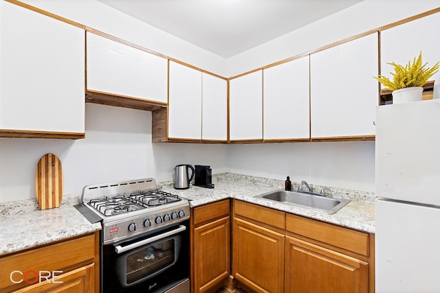 105 E 100th St Unit 4A, New York City, NY 10029 - kitchen with freestanding refrigerator, stainless steel range with gas stovetop, a sink, light countertops, and white cabinetry