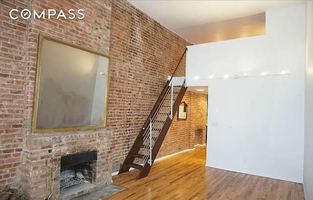 223 W 14th St Unit 1B, New York City, NY 10011 - unfurnished living room featuring wood finished floors, brick wall, a high ceiling, and a fireplace