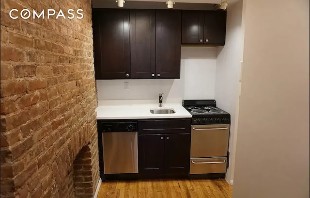 223 W 14th St Unit 1B, New York City, NY 10011 - kitchen with stainless steel appliances, brick wall, light wood finished floors, light countertops, and a sink