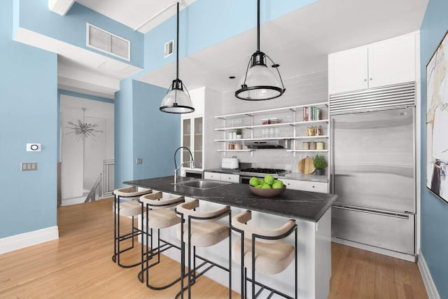 30 Main St Unit 2H, New York City, NY 11201 - kitchen with appliances with stainless steel finishes, a sink, under cabinet range hood, light wood-type flooring, and white cabinets