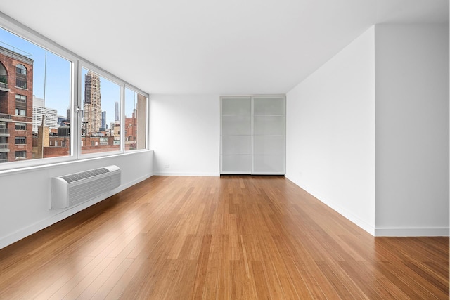353 E 72nd St Unit 20B, New York City, NY 10021 - spare room featuring a wall mounted AC, wood finished floors, and a city view