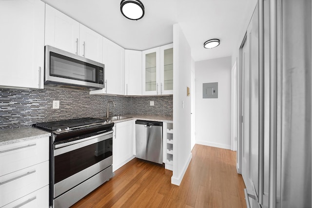 353 E 72nd St Unit 20B, New York City, NY 10021 - kitchen featuring stainless steel appliances, backsplash, light countertops, electric panel, and light wood-style floors