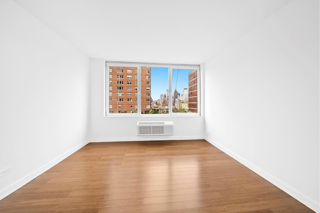 353 E 72nd St Unit 20B, New York City, NY 10021 - empty room featuring wood finished floors, a city view, and a wall unit AC