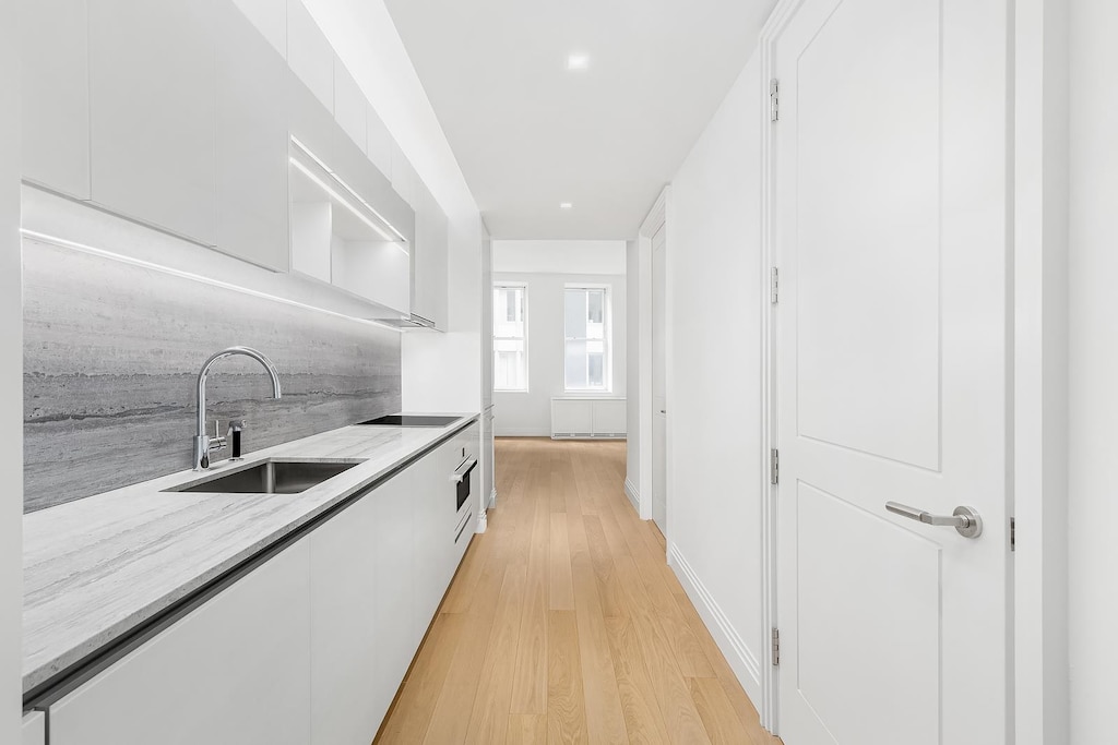 1 Wall St Unit 1116, New York City, NY 10005 - kitchen featuring a sink, white cabinets, modern cabinets, light wood finished floors, and open shelves