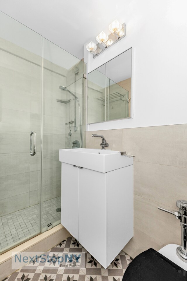 200 E 36th St Unit 13A, New York City, NY 10016 - full bathroom featuring a stall shower, vanity, tile walls, and toilet