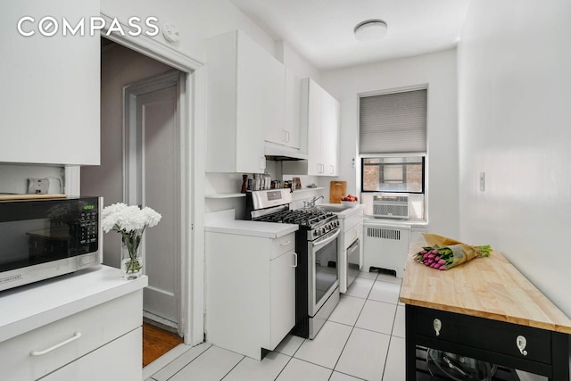 668 Riverside Dr Unit 3G, New York City, NY 10031 - kitchen featuring stainless steel appliances, radiator, white cabinetry, a sink, and light tile patterned flooring