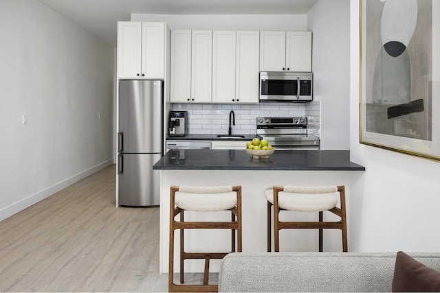 45 Cornelia St, New York City, NY 11221 - kitchen featuring appliances with stainless steel finishes, light wood-style flooring, dark countertops, and a kitchen bar