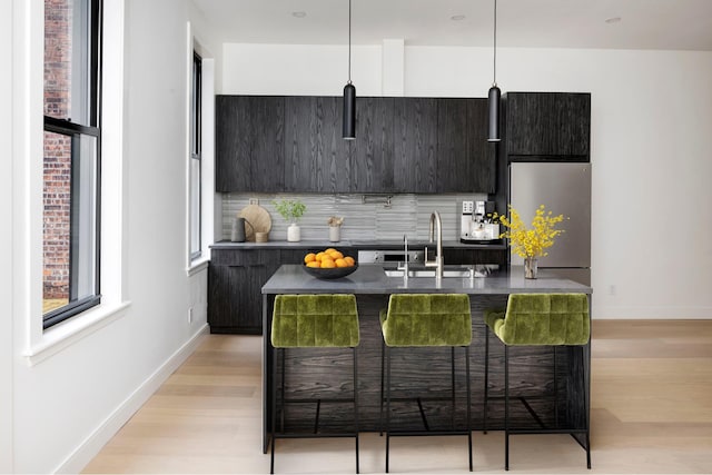 45 Cornelia St, New York City, NY 11221 - kitchen featuring a sink, modern cabinets, stainless steel fridge, light wood-style flooring, and baseboards