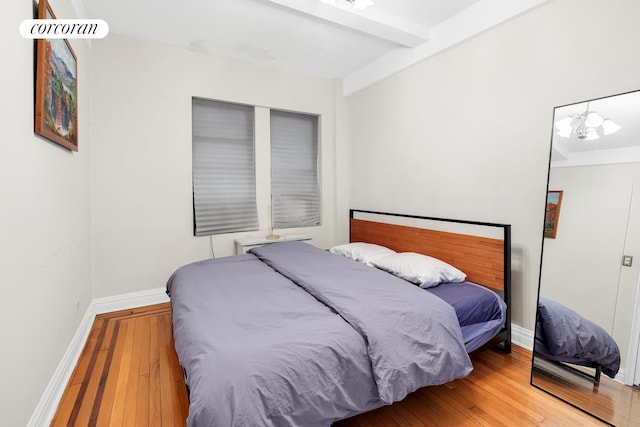 142 E 49th St Unit 2C, New York City, NY 10017 - bedroom with hardwood / wood-style floors, beamed ceiling, baseboards, and a chandelier