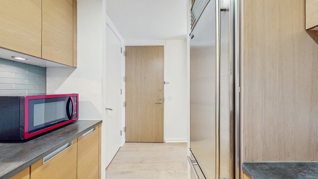 310 W 52nd St Unit 17A, New York City, NY 10019 - kitchen with dark countertops, light wood finished floors, light brown cabinetry, and tasteful backsplash
