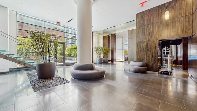 310 W 52nd St Unit 17A, New York City, NY 10019 - building lobby featuring floor to ceiling windows, a high ceiling, and wood walls