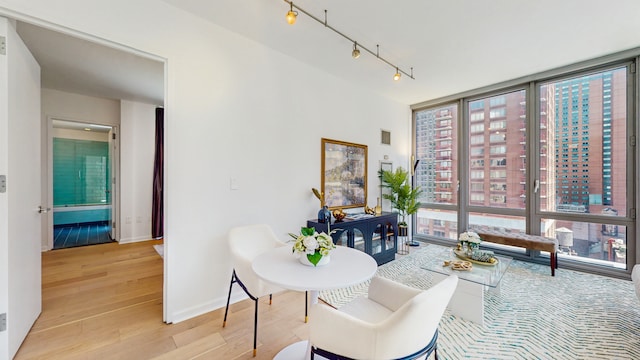 310 W 52nd St Unit 17A, New York City, NY 10019 - living area with expansive windows, light wood-style flooring, track lighting, and baseboards