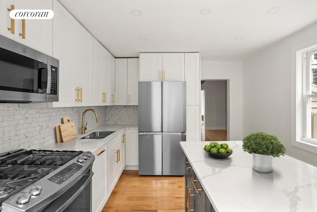 580 E 7th St, New York City, NY 11218 - kitchen featuring stainless steel appliances, a sink, white cabinetry, and backsplash