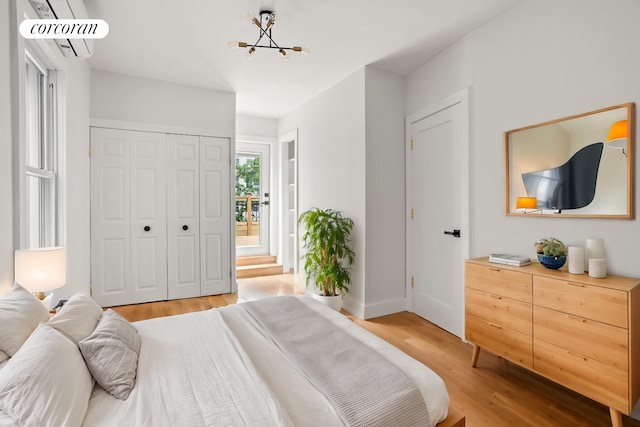 580 E 7th St, New York City, NY 11218 - bedroom featuring light wood-style flooring, a chandelier, a wall mounted air conditioner, a closet, and baseboards