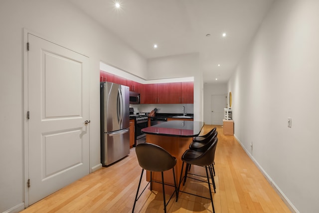 20 W St Unit 15H, New York City, NY 10004 - kitchen with stainless steel appliances, dark countertops, light wood-style flooring, recessed lighting, and a breakfast bar area