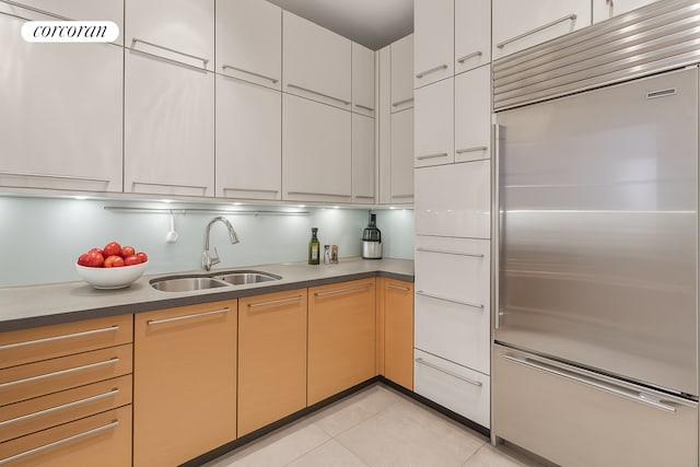 151 E 58th St Unit 42C, New York City, NY 10022 - kitchen with stainless steel built in fridge, a sink, light tile patterned floors, and dark countertops