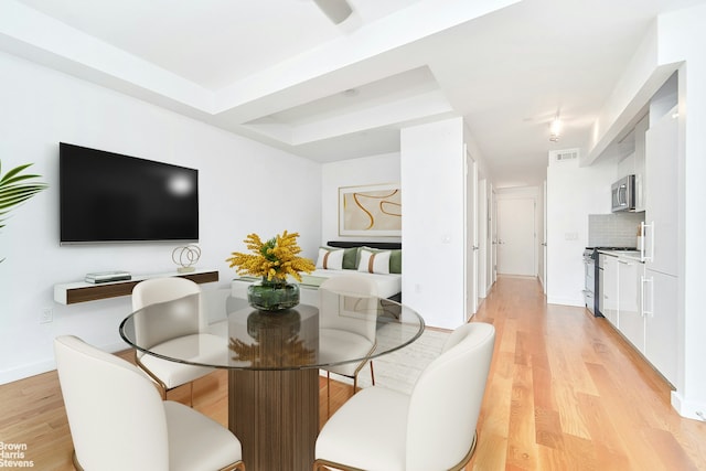 48 E 132nd St Unit 3E, New York City, NY 10037 - dining room featuring light wood-type flooring, a raised ceiling, and baseboards