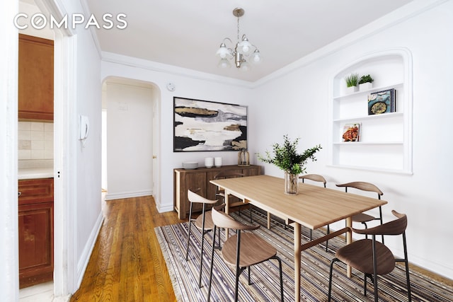 221 E 18th St Unit 5F, New York City, NY 11226 - dining area featuring arched walkways, a chandelier, wood finished floors, built in features, and ornamental molding