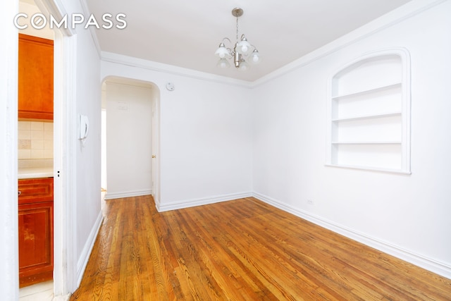 221 E 18th St Unit 5F, New York City, NY 11226 - empty room with arched walkways, a chandelier, wood finished floors, built in features, and crown molding