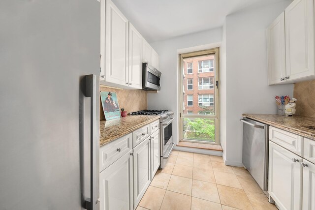 201 E 80th St Unit 4A, New York City, NY 10021 - kitchen with stainless steel appliances, backsplash, white cabinets, and light stone counters