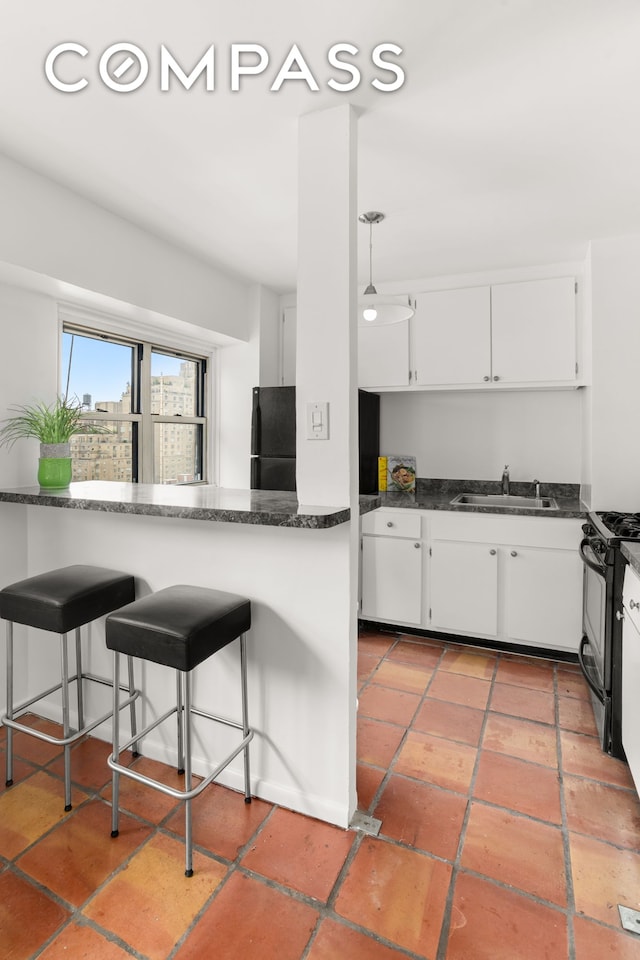 609 Columbus Ave Unit 14E, New York City, NY 10024 - kitchen with black appliances, white cabinetry, a kitchen bar, and dark stone countertops