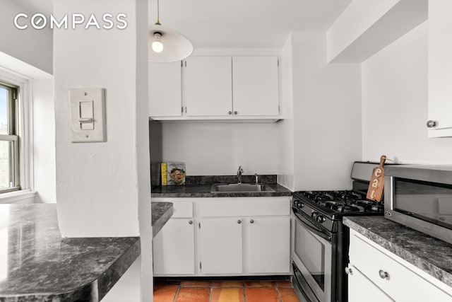 609 Columbus Ave Unit 14E, New York City, NY 10024 - kitchen with appliances with stainless steel finishes, dark countertops, white cabinetry, and pendant lighting