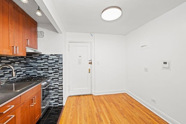 15 Oliver St Unit 3C, New York City, NY 11209 - kitchen with stainless steel gas range, backsplash, dark countertops, wood finished floors, and under cabinet range hood