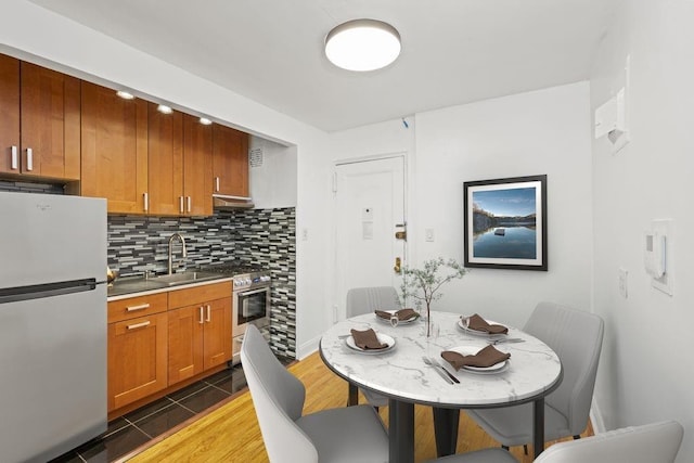 15 Oliver St Unit 3C, New York City, NY 11209 - kitchen with stainless steel appliances, backsplash, brown cabinets, and light wood-style flooring