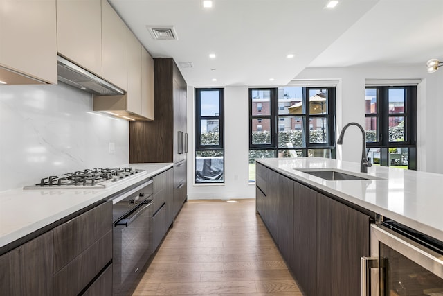 11 Hancock Pl Unit 304, New York City, NY 10027 - kitchen with a sink, beverage cooler, black oven, light wood-style flooring, and stainless steel gas cooktop