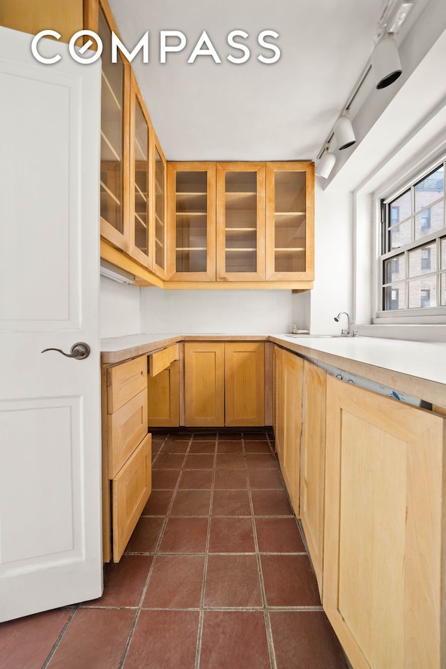 12 E 88th St Unit Ph11/12B, New York City, NY 10128 - kitchen with glass insert cabinets, light countertops, dark tile patterned floors, track lighting, and light brown cabinets