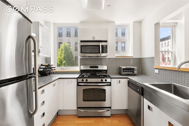 318 Knickerbocker Ave Unit 2A, New York City, NY 11237 - kitchen with appliances with stainless steel finishes, white cabinets, decorative backsplash, and a sink