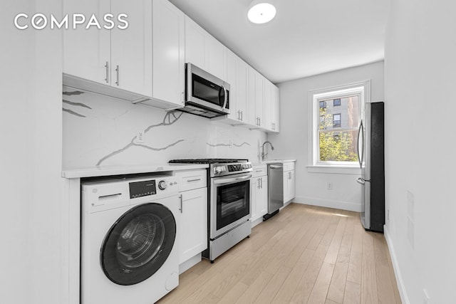 1050 Sterling Place, New York City, NY 11213 - kitchen featuring washer / clothes dryer, appliances with stainless steel finishes, light countertops, white cabinets, and backsplash