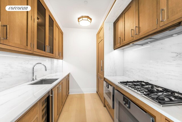 30 Park Pl Unit 60C, New York City, NY 10007 - kitchen with a sink, stainless steel gas cooktop, brown cabinets, light wood-type flooring, and baseboards