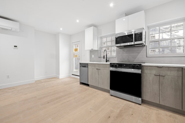 113 W 13th Street Building, New York City, NY 10011 - kitchen with stainless steel appliances, a wall mounted air conditioner, light wood-type flooring, light countertops, and a sink