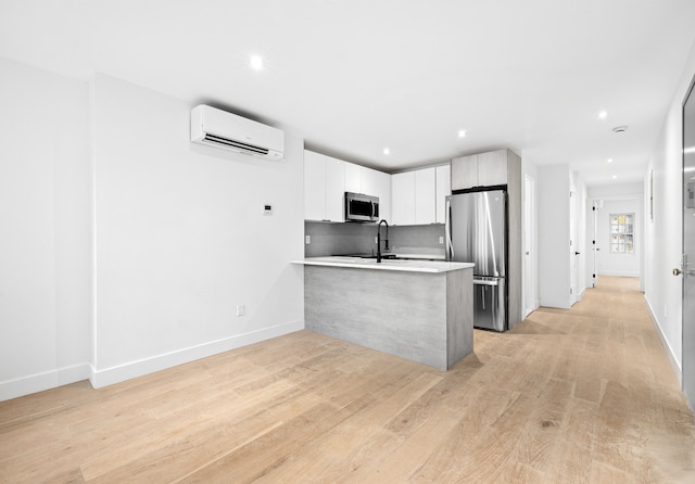 113 W 13th Street Building, New York City, NY 10011 - kitchen featuring appliances with stainless steel finishes, a wall mounted air conditioner, a peninsula, light countertops, and backsplash