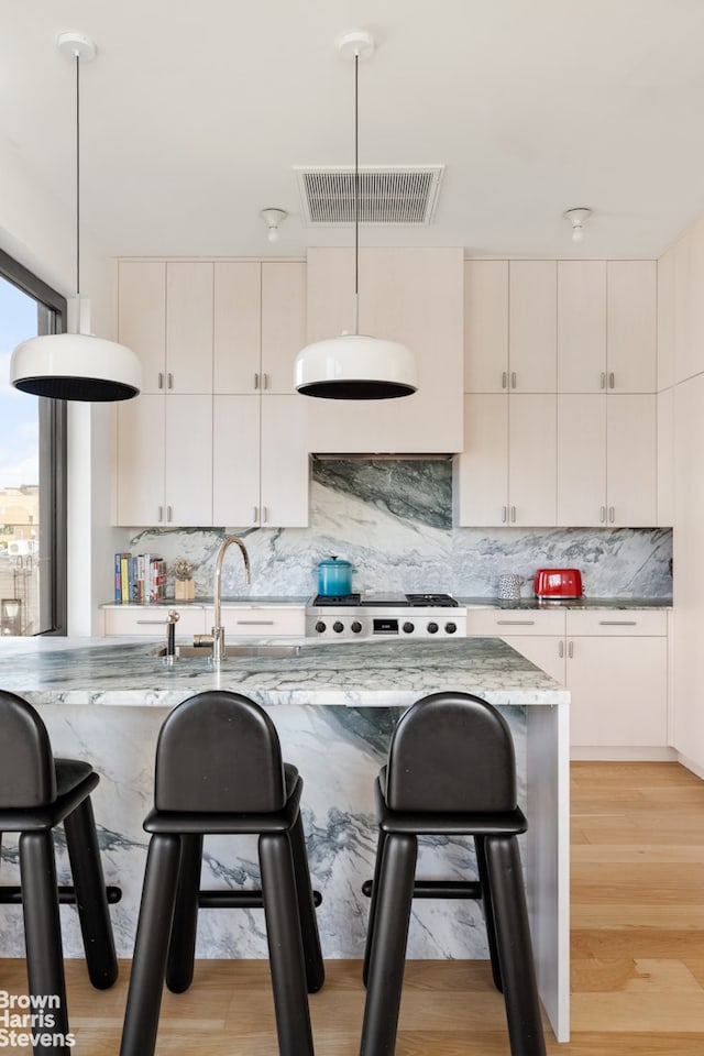 207 N 5th St Ph, Ph, New York City, NY 11211 - kitchen featuring a breakfast bar, decorative backsplash, and light stone countertops