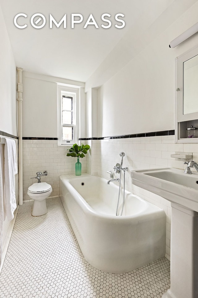 24 Monroe Pl Unit 7D, New York City, NY 11201 - full bathroom with tile walls, tile patterned flooring, wainscoting, toilet, and a garden tub