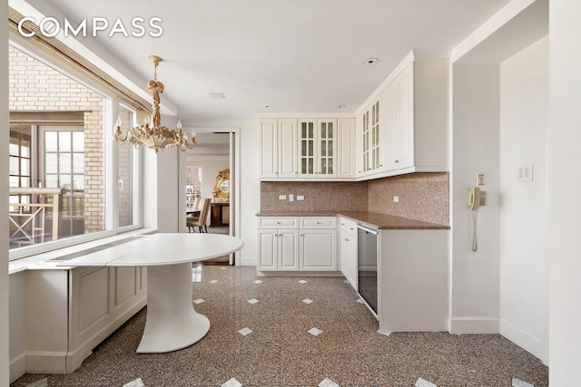 1049 5th Ave Unit Ph20, New York City, NY 10028 - kitchen featuring baseboards, glass insert cabinets, decorative backsplash, white cabinets, and granite tiled floors