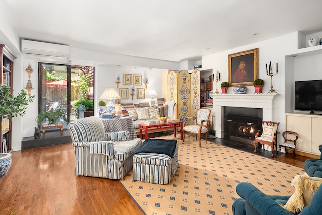 56 W 71st St Unit 1B, New York City, NY 10023 - living area featuring a wall mounted air conditioner, a fireplace with flush hearth, and wood finished floors