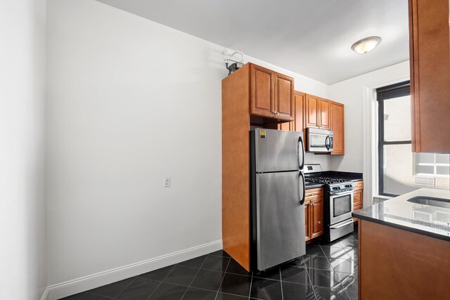 401 W End Ave Unit 6E, New York City, NY 10024 - kitchen with appliances with stainless steel finishes, dark stone countertops, and brown cabinetry